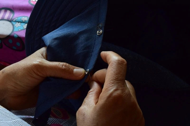 一个女人在衬衫上缝制衣服铆钉